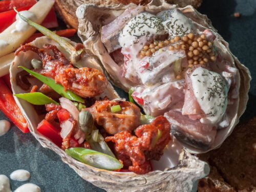 eingelgter-Herring-in-Joghurt-und-Meeretich-in-austernsachale-auf-dunklem-Teller-und-blauem-Hintergrund