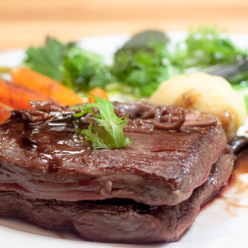 Angus iron flank steak mit gegrillten Möhren und Kartoffelnocken auf Teller in Nahaufnahme