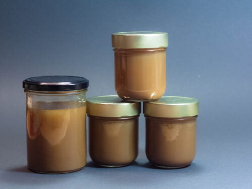 Fertiger Rinderfond in Schraubglaeser abgefuellt vor blauem Hintergrund