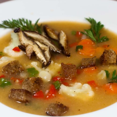 Gemuesesuppe-mit-verschiedenen-Gemuesesorten-und-Croutons-m-Teller-als-Nahaufnahme