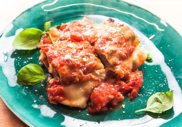 Canneloni-mit-Tomatensauce-auf-gruenen-Teller-mit-Basilikum-und-Parmensan-