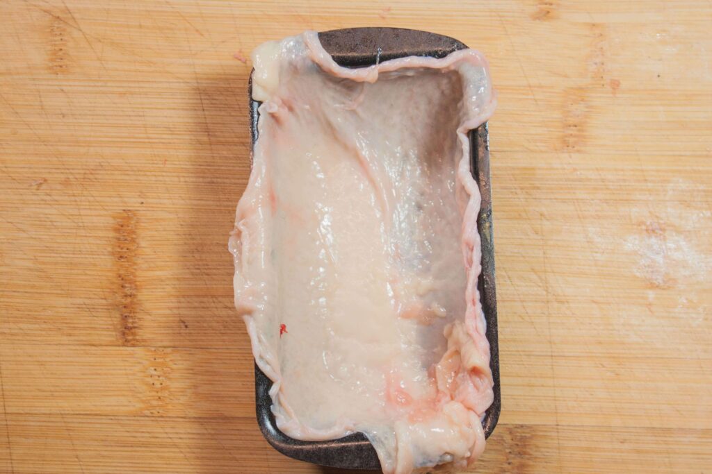 Hähnchen pate 7 https://oxbe.de/wp-content/uploads/2023/01/download.png Haehnchenhaut-in-schale-ausgelegt-auf-hellerm-Schneidebrett