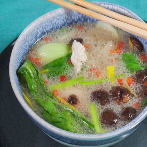 Huehnersuppe-mit-pach-choi-shiitake-Pilzen-und-glasnudeln in einer blauen Schüssel