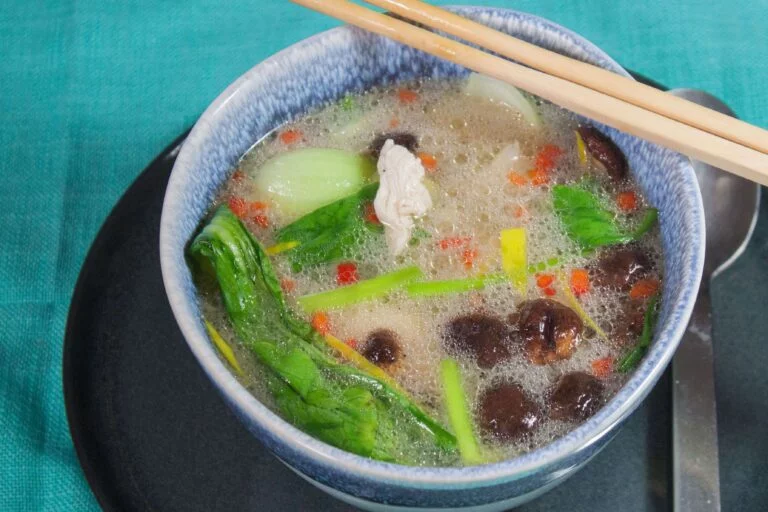 Huehnersuppe-mit-pach-choi-shiitake-Pilzen-und-glasnudeln in einer blauen Schüssel
