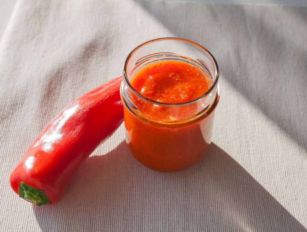 paprikasauce 2 https://oxbe.de/wp-content/uploads/2023/01/download.png Paprikasauce-im Glas-auf-Tuch-im-tageslicht-