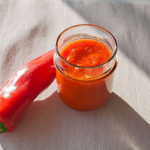 Paprikasauce-im Glas-auf-Tuch-im-tageslicht-