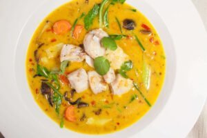 curry-fischsuppe-mit-kokosmilchpack-choi-und-shiitakepilzen-in-weissem-Teller