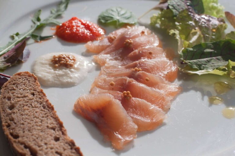 Garved-Forelle-auf-weissen-Teller-angerichtet-mit-Salat-Meerettich-und-Senfkaviar-