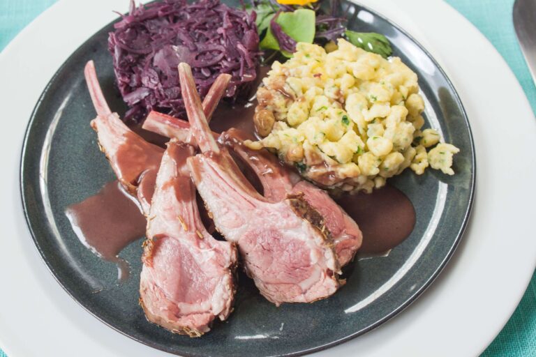 Lammkarree 2 https://oxbe.de/wp-content/uploads/2023/01/download.png Lammkarree-mit-Baerlauchspaezle-und-Rotkohl-in-dunkler-Sauces-auf-shwarzen-Teller