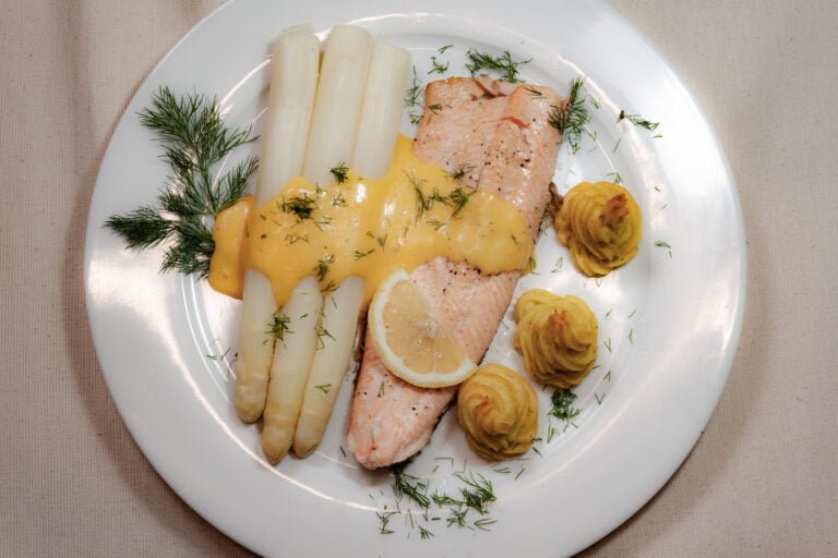Saibling-mit-Spargel-Prinzesskartoffeln-und-Sacue-Hollandaise-auf-weissem-Teller-