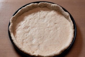 Fugazzeta 4 https://oxbe.de/wp-content/uploads/2023/01/download.png Hefeteig-in-Pizzaform-ausgelegt-auf-Arbeitsflaeche
