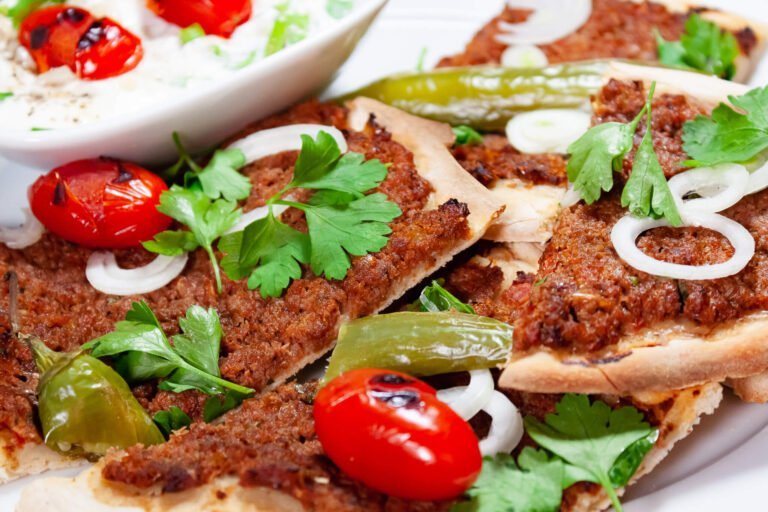 Lahmacun 5 https://oxbe.de/wp-content/uploads/2023/01/download.png Lahmacun-mit-Petersilie-gegrillten-Peperonie-Tomate-und-Zwiebeln-auf-einem-weissen-Teller.