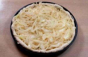 Fugazzeta 6 https://oxbe.de/wp-content/uploads/2023/01/download.png Zwiebeln-auf-Mozzarella-in-schwarzem-BAckblech-auf-Arbeitsplatte