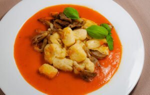 In-Butter-gebraeunte-Gnocchi-auf-Paprikasauce-mit-austernpilzen-und-frischen-BAsilikum-in-weissem-Telle
