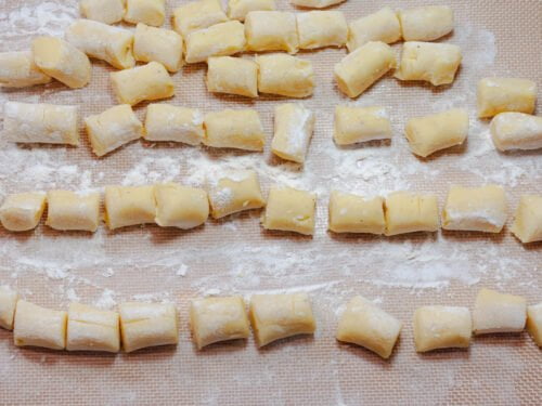 Gnocchi 11 https://oxbe.de/wp-content/uploads/2023/01/download.png In-Butter-gebraeunte-austernpilze-in-Pfanne-auf-ArbeitsbrettGEschnittene-Gnocchi-auf-bemehlter-Silikonmatt