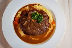 Klassisches-Ossobuco-mit-Gremolata-Kartoffelpueree-und-dunkler-Sauce-auf-weissen-Teller