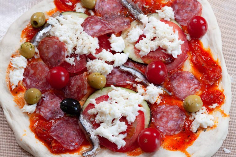 Salami Pizza 4 https://oxbe.de/wp-content/uploads/2023/01/download.png Pizzateig-belegt-mit-MozarellaTomatenAuberginen-und-Anchovis-fertig-zum-Backen