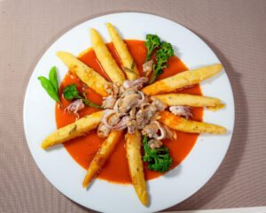 Schupfnudeln mit Meeresfrüchten stangenbrokolie in Tomatensacue auf weissem tellerauf Arbeitsbrett fertig zum Kochen