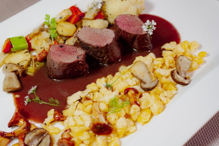 Wildhasenrücken auf weissem Teller mit Späzle geröstetem Wurzelgemüse und Pilzen-3