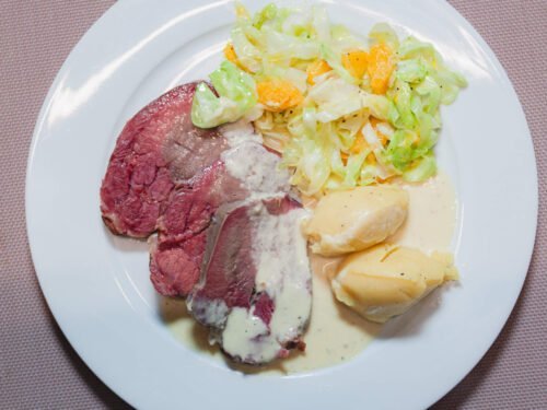 Rinderzunge in mit orangekohl kartoffelpüree und merretich shanesauce auf weissem teller