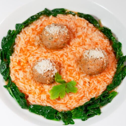 kalbsklößchen in tomatenrreis und spinat in weißem telle