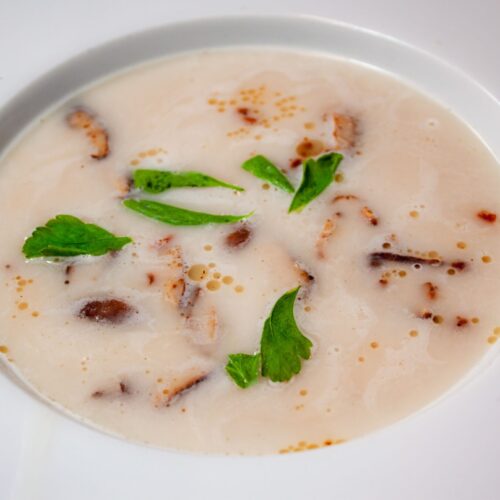 Bohnensuppe mit shitakke und Petersilie in weißem Teller