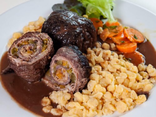 Geschmorte Rimderroulade mit shenespaezle,butterkarotten und dunkler sacue auf weissem teller